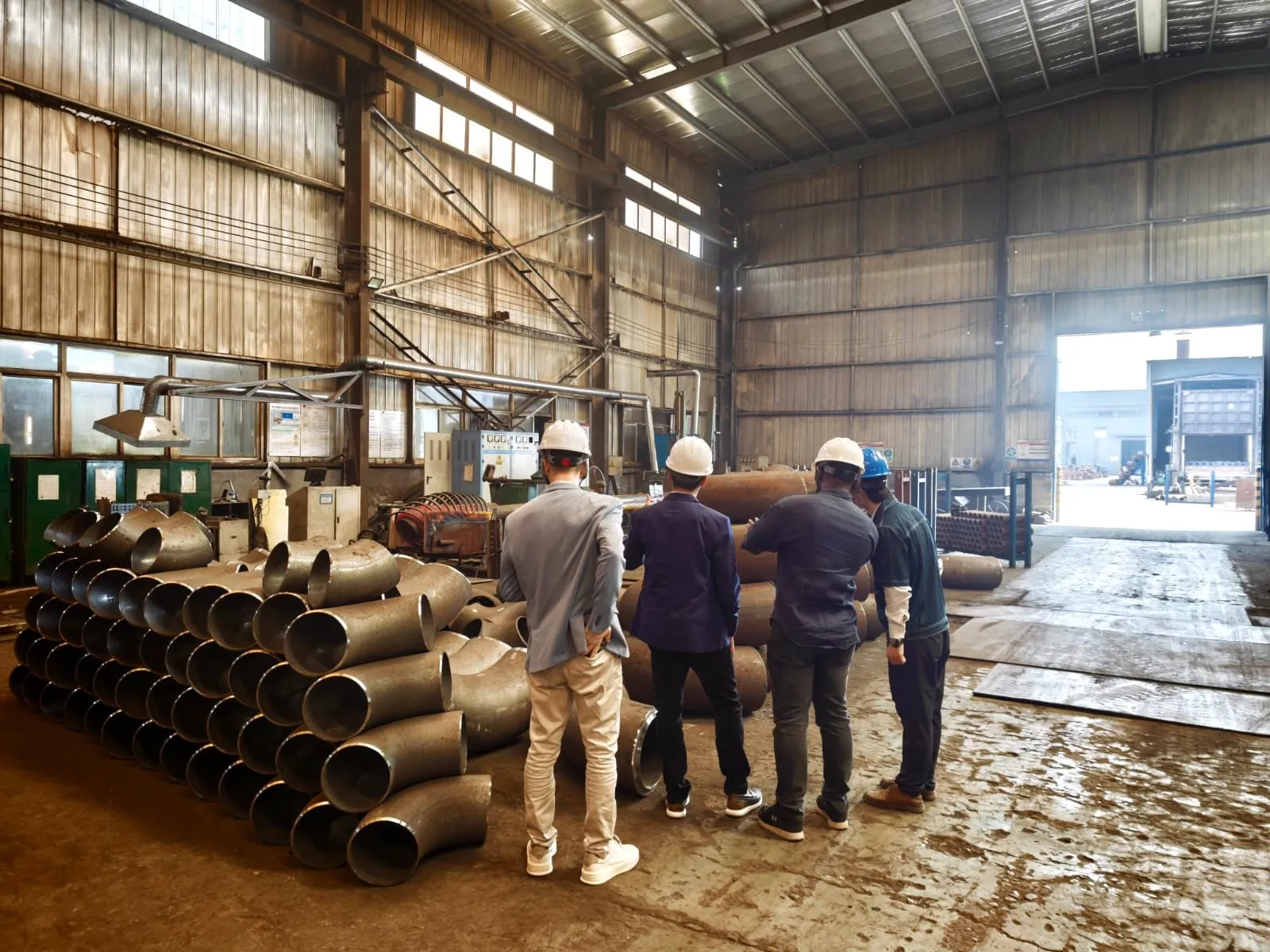 Clientes com capacete a visitar uma fábrica de curvas para tubagem